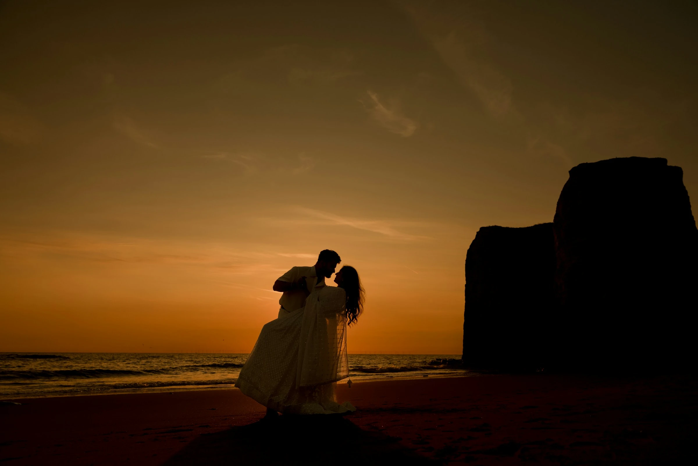 Couple enjoying a romantic honeymoon by the beach at sunset